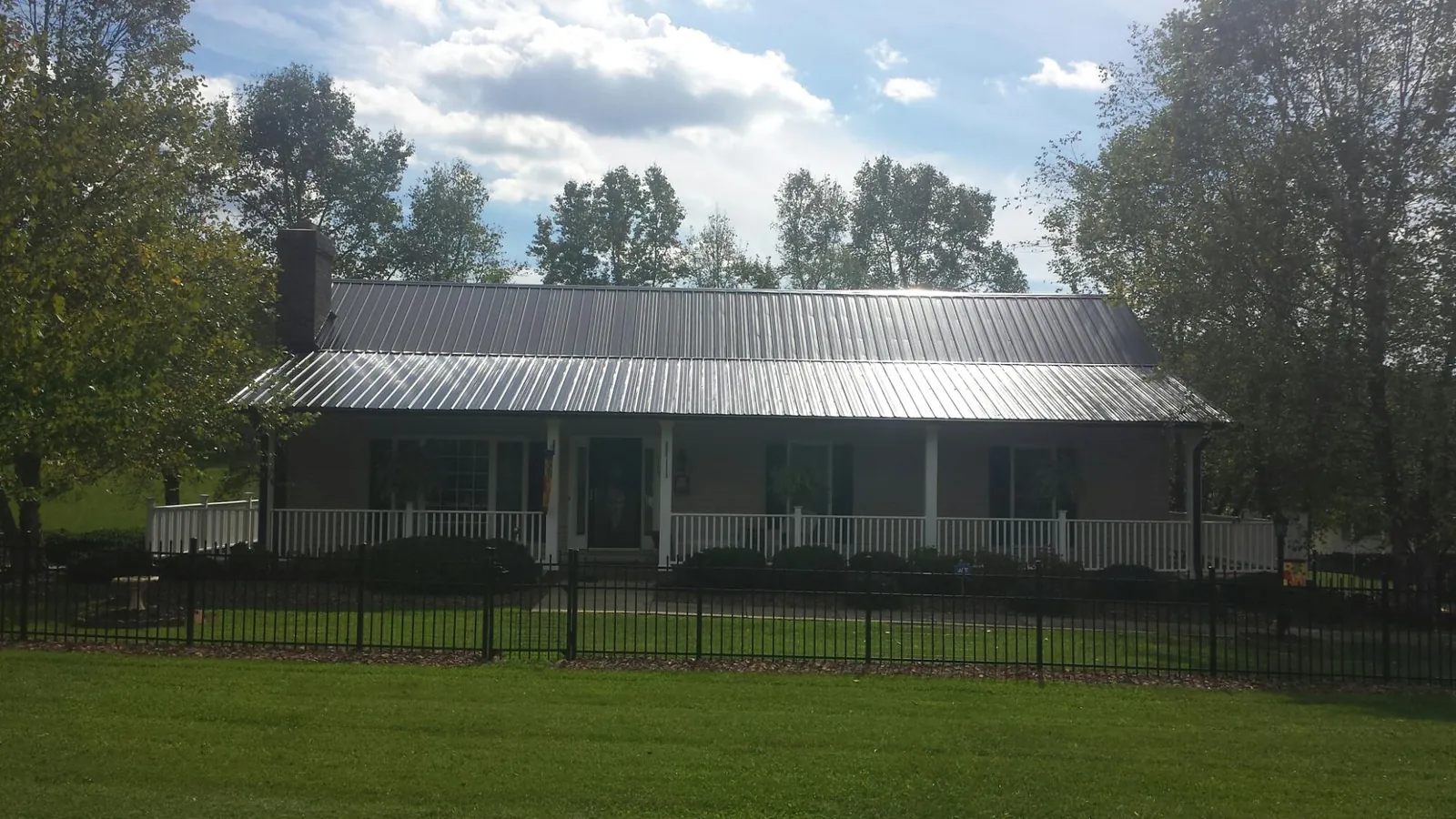 Gray metal roof on a brick ranch with a full width front porch — Gutter Guard Installation work by our crew in Calhoun